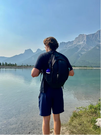 Emile, sac sur le dos, face à un lac de montagne